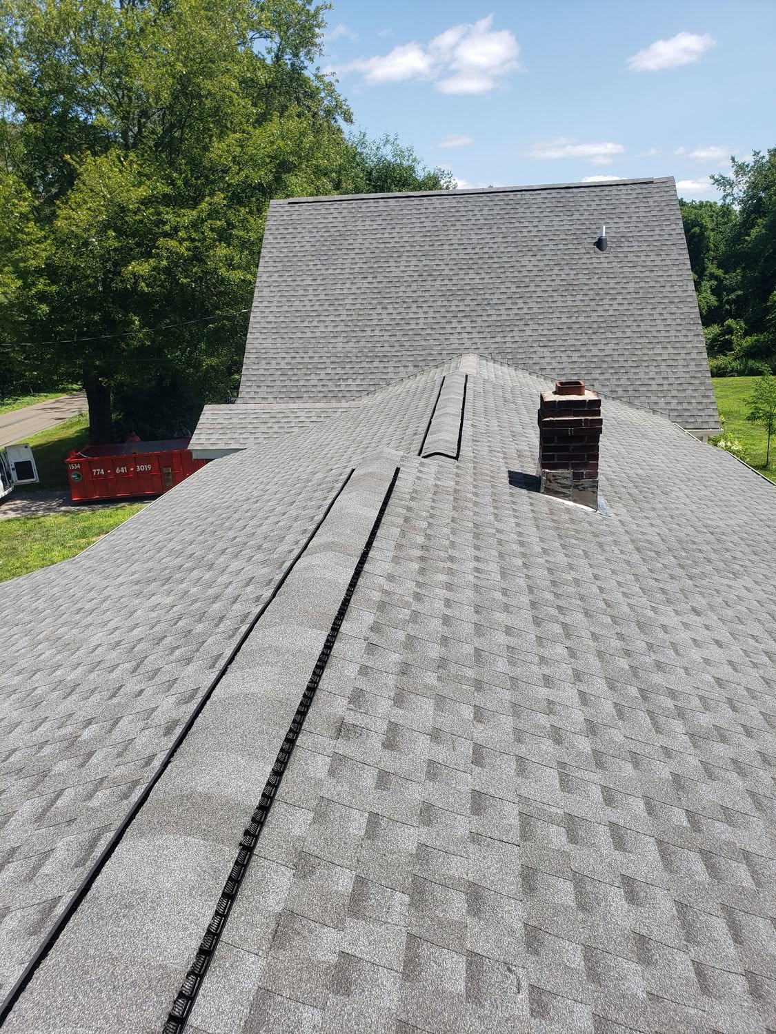 New asphalt shingle roof installation on residential home with chimney and ridge vents