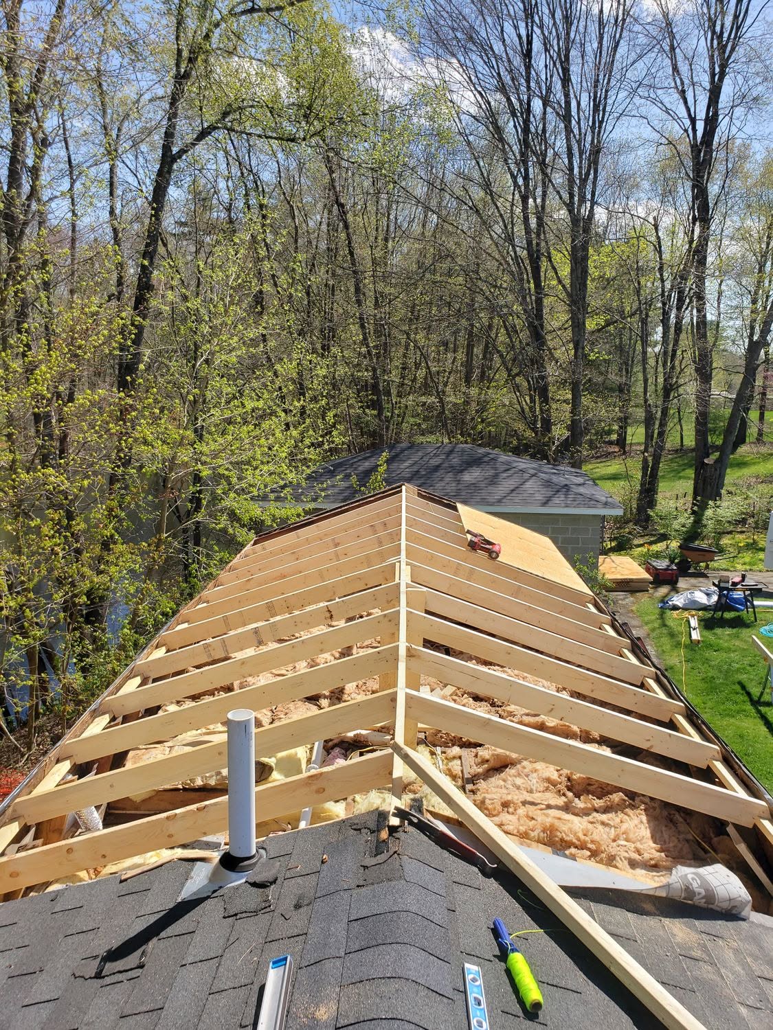 Roof framing construction with wooden trusses and insulation in wooded residential area